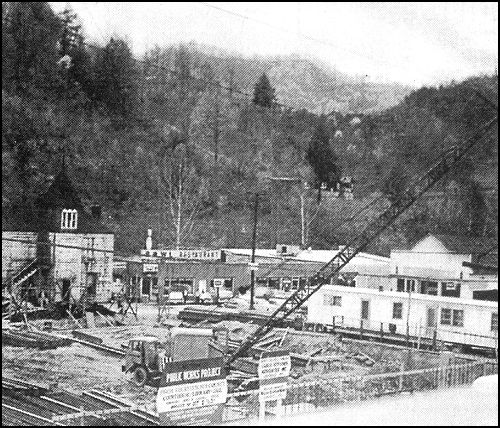This photo shows the early excavation necessary to construct the 1960's courthouse. The building with a tower at the rear of the excavation is the old Letcher County jail, a stone structure built in 1907 just behind the courthouse. By the '60's, the jail was in such bad repair that prisoners had little difficulty in pushing the bars apart, climbing out the windows and sliding down a rope of sheets to freedom.