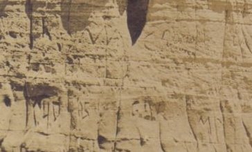 Detail of 'Two men climbing Cowboy Rock near Sun City, Kansas' showing graffiti carved into the stone pillar.