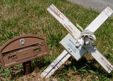 A cross on the ground next to a mailbox

AI-generated content may be incorrect.